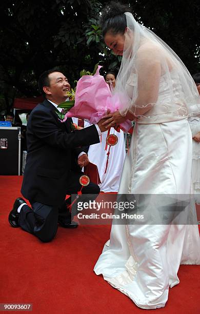 Groom presents flowers to the bride during a disabled persons group wedding held to mark the Qixi Festival, the Chinese equivalent of Valentine's Day...