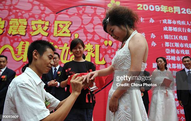 Groom puts the wedding ring on the bride's finger during a disabled persons group wedding held to mark the Qixi Festival, the Chinese equivalent of...