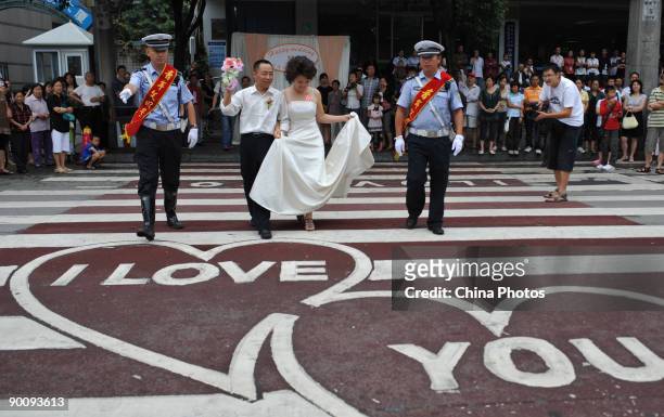 Policemen help a couple cross the 'Love Zebra Crossing' during a disabled persons group wedding held to mark the Qixi Festival, the Chinese...