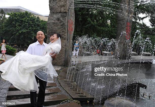 Groom holds his bride who lost her arms in the Sichuan earthquake last year, as they pose for pictures during a disabled persons group wedding held...