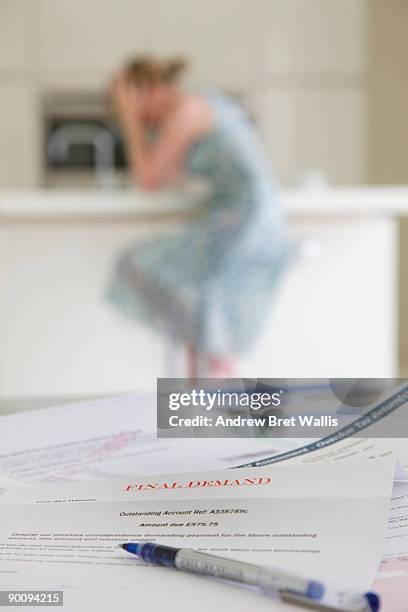 a stack of overdue bills and a woman head in hands - past due englischer satz stock-fotos und bilder