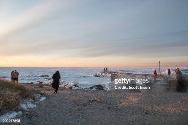 Onlookers gather to photograph and watch the ice that covers Cape Cod Bay on January 3, 2018 in Orleans, Massachusetts. A winter storm is hitting the...