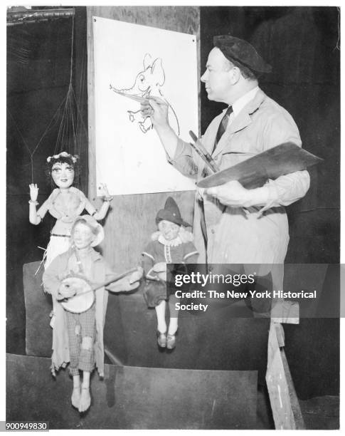 Puppeteer Tony Sarg at easel, marionettes at fore, 1939.