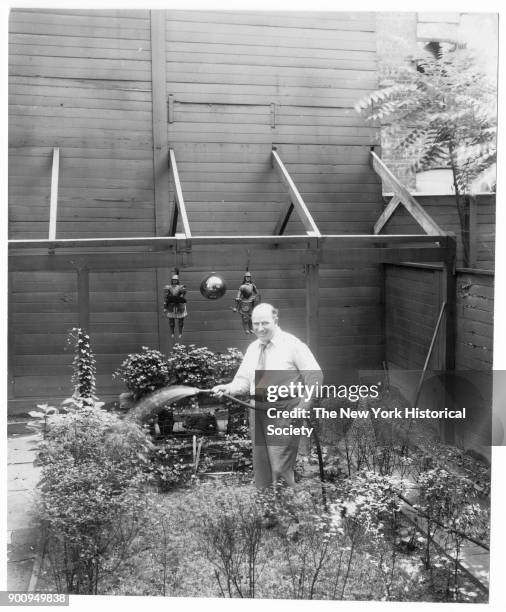 Puppeteer Tony Sarg, in shirtsleeves and tie watering plants in garden , 1922.