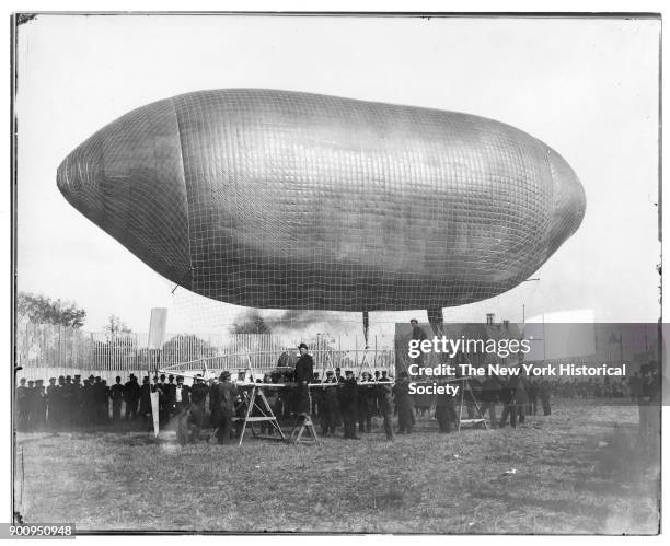 Airship 'California Arrow' resting on sawhorses and held by several men; Thomas Baldwin standing on small sawhorse, Roy Knabenshue standing on...