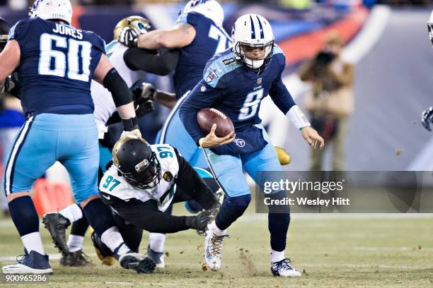 Marcus Mariota of the Tennessee Titans runs the ball and gets away from the tackle of Malik Jackson of the Jacksonville Jaguars at Nissan Stadium on...