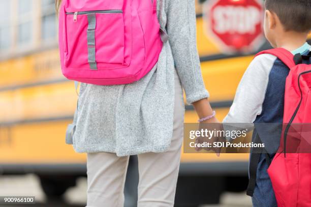 兄と妹は学校のバスの前で手を保持します。 - bus front ストックフォトと画像