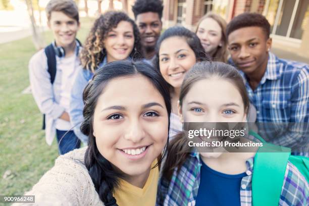 diverse group of teens looking at camera taking selfie at high school - youth culture stock pictures, royalty-free photos & images