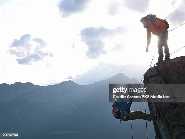 woman rappels (abseils) cliff, man directs on top - extreme sports team stock pictures, royalty-free photos & images