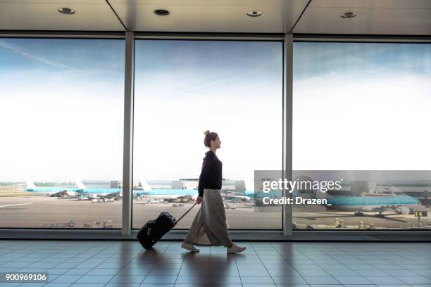 次の便にスーツケースを持つ女性掲示板に起こっています。 - airport ストックフォトと画像