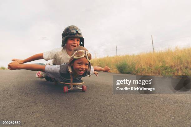 jonge jongens stel je vliegen op skateboard - de stoute schoenen aantrekken stockfoto's en -beelden