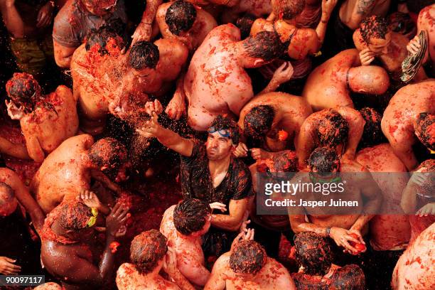 Reveller throws tomatoes amid people pelting each other during the world's biggest tomato fight at La Tomatina festival on August 26, 2009 in Bunol,...