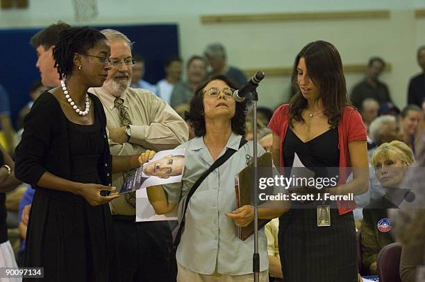 Lyndon LaRouche supporter holding a sign depicting President Obama with a Hitler-style mustache is hurried away from the microphone during a town...