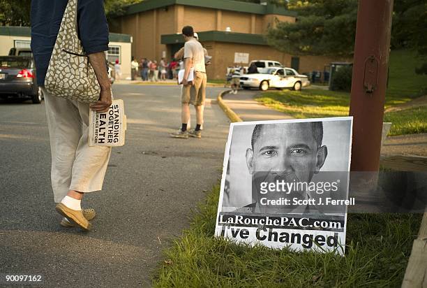 Healthcare reform supporter walks by a sign belonging to Lyndon LaRouche suppoerts outside a town hall meeting in Germantown, Md., hosted by Rep....