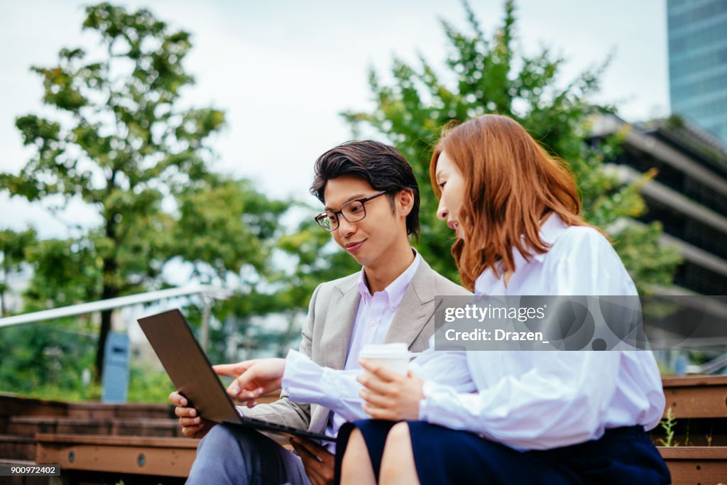 Japanese business people using laptop on coffee break