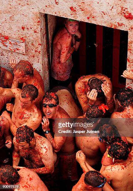 Girl shelters in the doorway of a house as revellers pelt each other with tomatoes during the world's biggest tomato fight at La Tomatina festival on...