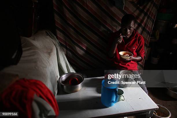 Teenager eats a meal in a makeshift kitchen August 26, 2009 in the Kibera slum in Nairobi, Kenya. The non-governmental organization Concern, in...