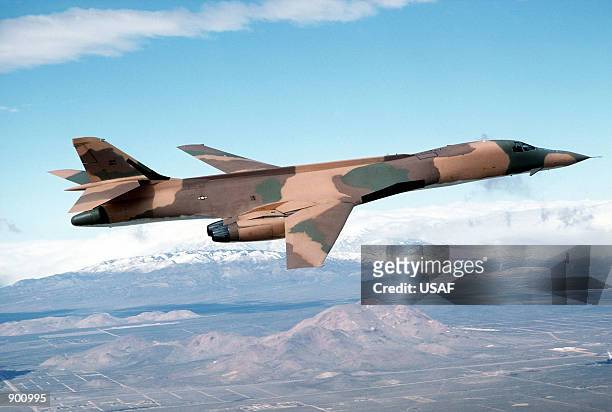 Right side view of a B-1 bomber aircraft flying over the base range during testing and evaluation.