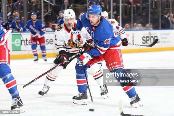 Brendan Smith of the New York Rangers skates with the puck against Patrick Sharp of the Chicago Blackhawks at Madison Square Garden on January 3,...