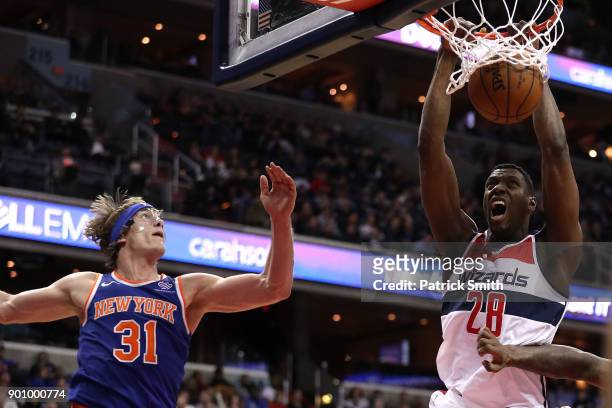 Ian Mahinmi of the Washington Wizards dunks in front of Ron Baker of the New York Knicks during the second half at Capital One Arena on January 3,...
