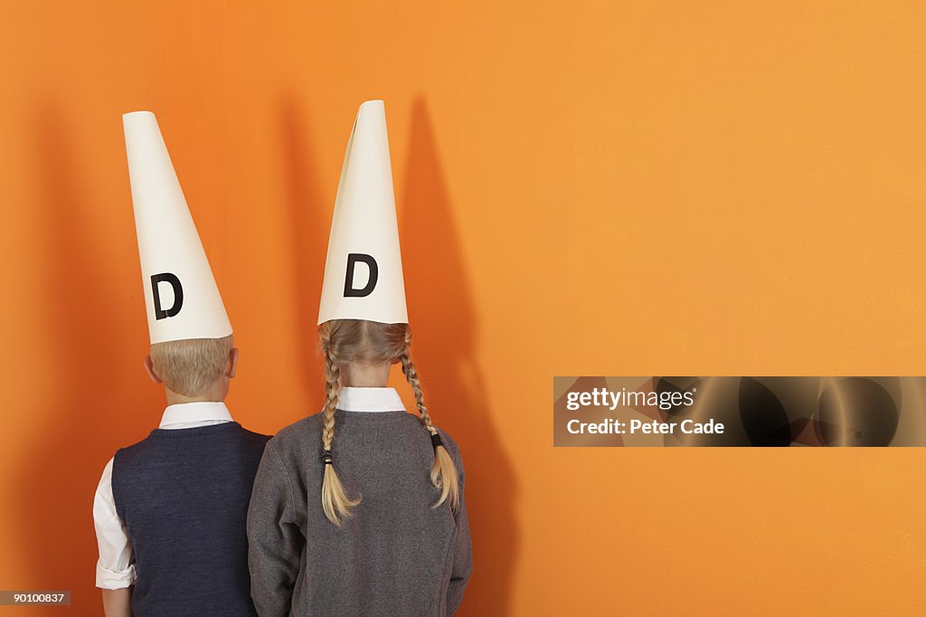 Boy and girl in corner wearing dunces hat