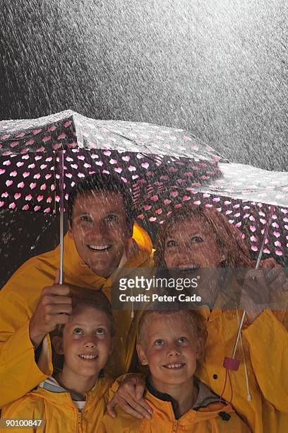 family in rain under umbrellas - girl rain night stock pictures, royalty-free photos & images
