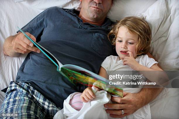 four-year-old girl reading book with her dad.  - 2 year old blonde girl father ストックフォトと画像