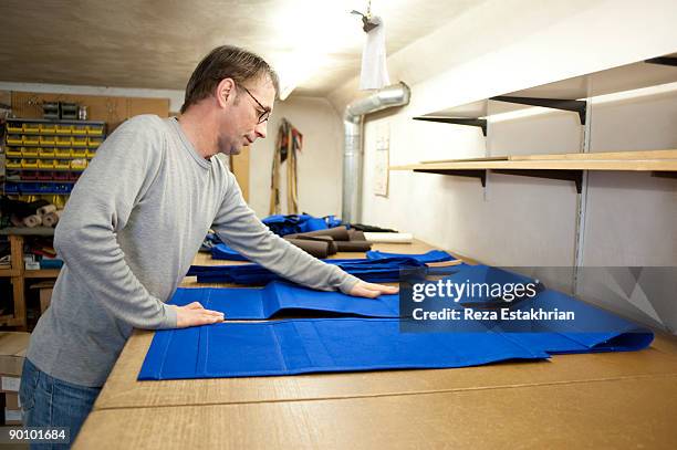 man prepares parts of canvas bags on table - upholstered furniture stock pictures, royalty-free photos & images