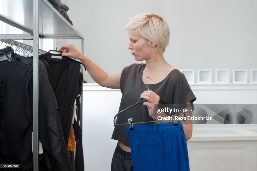 Young woman selects garments to try on in fashion 