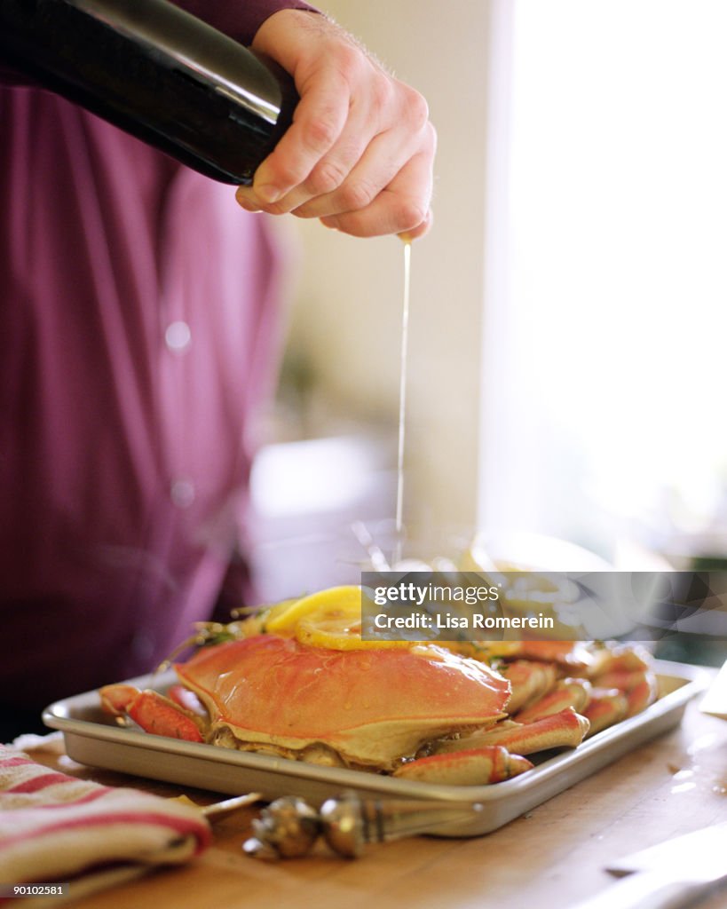 Man pouring olive oil on whole dungeness crabs