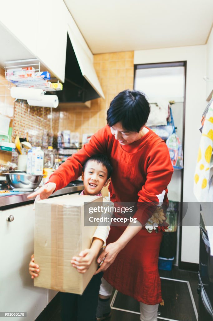 Boy Helping Mother Carrying Box