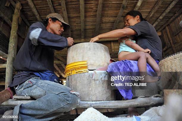 In this photo taken on August 9, 2009 a family grinds corn seeds for food in a village in Surala town, province of south Cotabato. Data showed the...