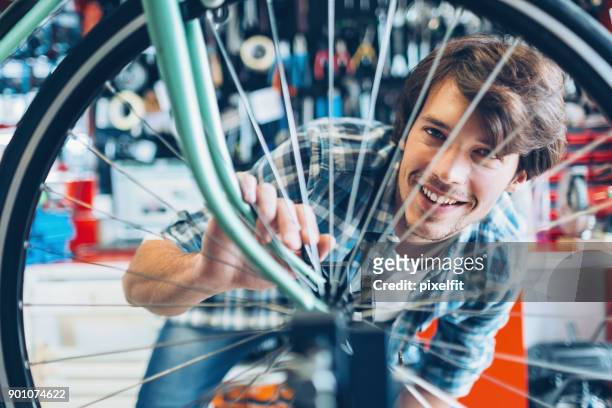 lächelnde fahrradmechaniker - fahrrad reparieren stock-fotos und bilder
