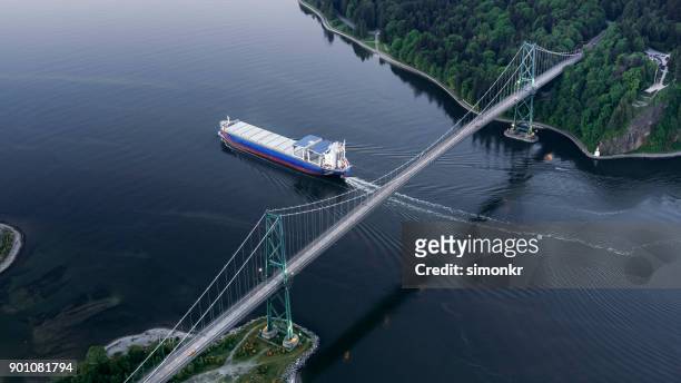 lions gate bridge with cargo ship - vancouver lions gate stock pictures, royalty-free photos & images