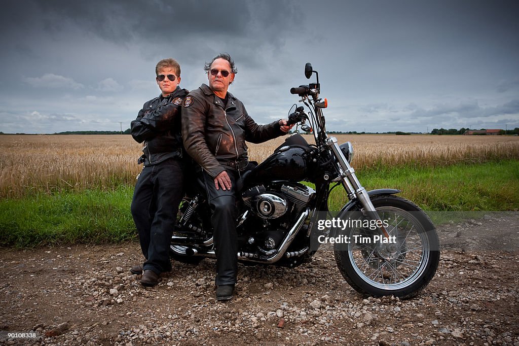 Man and son sitting on a motorcycle.