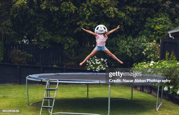 young girl jumping on trampoline with panda mask on. - trampoline stock-fotos und bilder