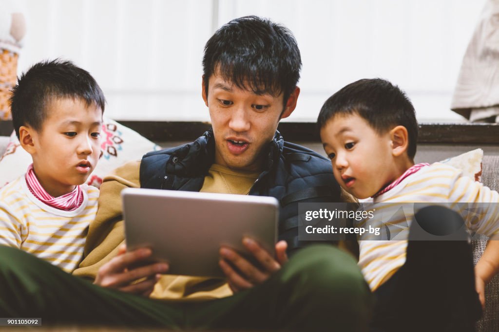 Far läsa berättelser på digitala tablett för hans söner