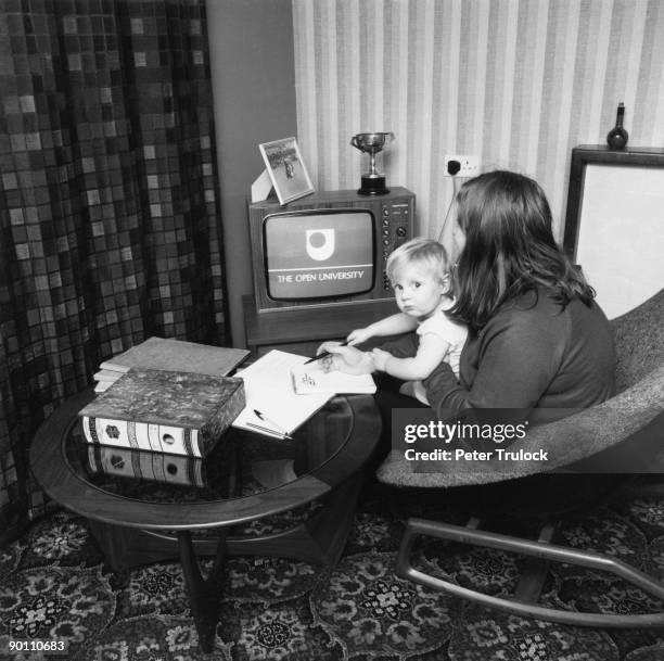 Student watching an Open University broadcast on TV with her child on her lap, 9th February 1971. A distance learning university, the Open University...