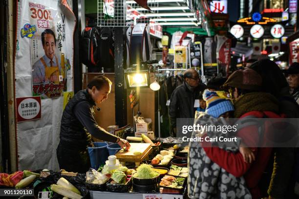 People watch a salesman demonstrate a kitchen implement as he sells his wares in Ameya Yokocho market on January 4, 2018 in Tokyo, Japan. Ameya...