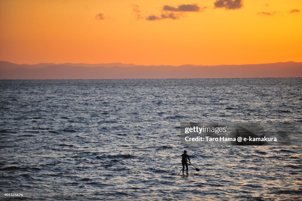 A surfer on sunset beach in Kamakura city in Kanagawa prefecture in Japan