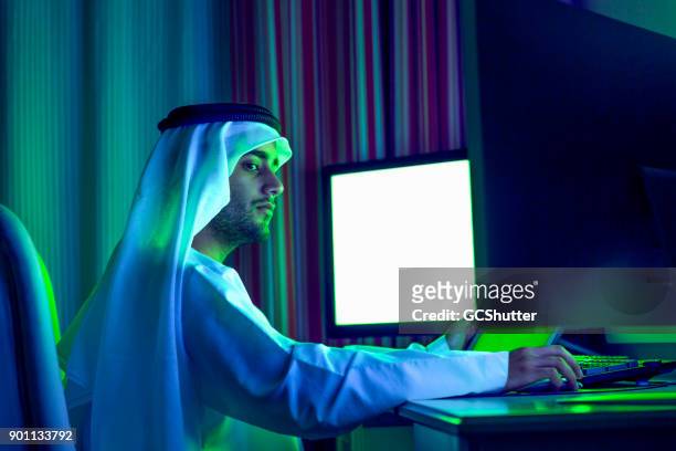 focused young arab working for his company from home at night - bahrain stock pictures, royalty-free photos & images