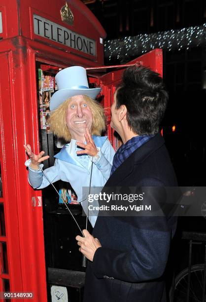 Jim Carrey poses with his puppet Harry Dunne, from Dumb and Dumber, inside a London telephone box, covered in call girl advertising, after dining at...