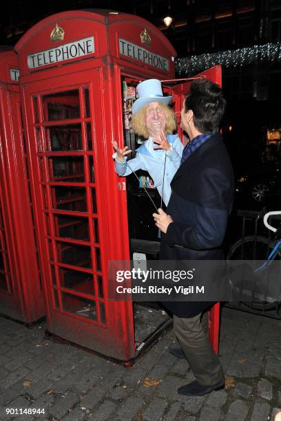 Jim Carrey poses with his puppet Harry Dunne, from Dumb and Dumber, inside a London telephone box, covered in call girl advertising, after dining at...