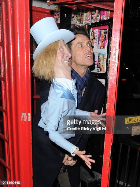 Jim Carrey poses with his puppet Harry Dunne, from Dumb and Dumber, inside a London telephone box, covered in call girl advertising, after dining at...