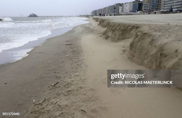 People walk on the beach in Blankenberge after storm Eleanor caused tides to swell earlier in the week on January 4, 2018. - Eleanor, the fourth...