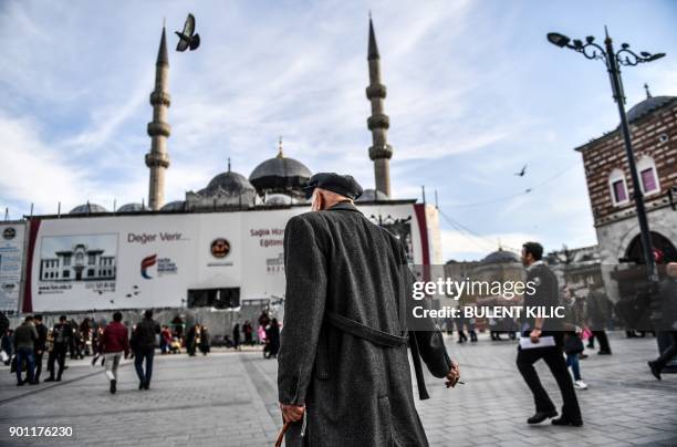Man walks in front of the New Mosque at Eminonu Square on the European side of Istanbul on January 4, 2018. / AFP PHOTO / Bulent Kilic