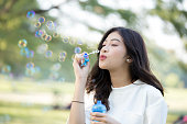 Attractive aAsian Woman blow bubble at outdoor place. Woman lifestyle concept.