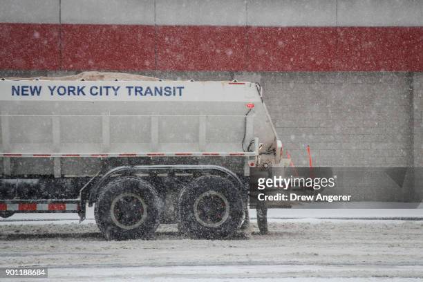 Truck dumps road salt on Atlantic Avenue, January 4, 2018 in the Brooklyn borough of New York City. As a major winter storm moves up the Northeast...