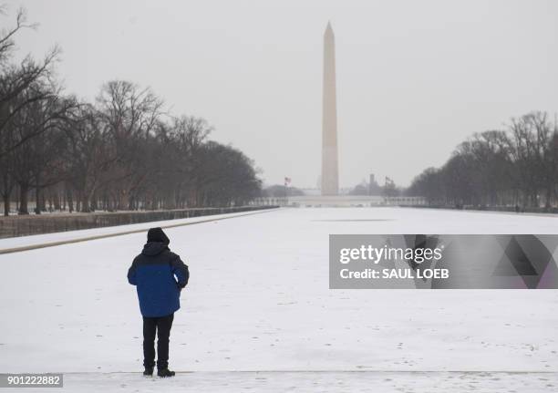 Man looks out over a frozen Lincoln Memorial Reflecting Pool on the National Mall during a snow storm in Washington, DC, January 4, 2018. A giant...