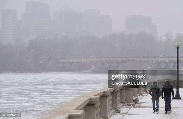 People walk along a frozen Potomac River during a snow storm in Washington, DC, January 4, 2018. A giant winter "bomb cyclone" walloped the US East...